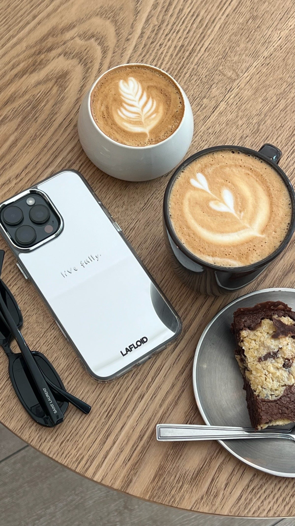 Funda espejo LAFLOID personalizada con "live fully" junto a un café, lifestyle